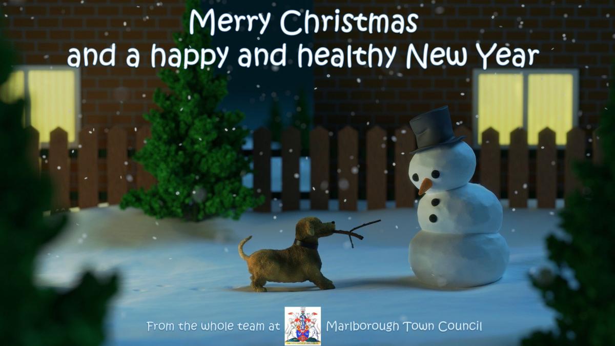 a snowy scene. A dog holds twigs in its mouth, offering them to a snowman. Caption reads merry christmas and a happy and healthy new year