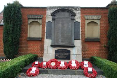 wreaths of poppies lie beneath a brick and stone cenotaph