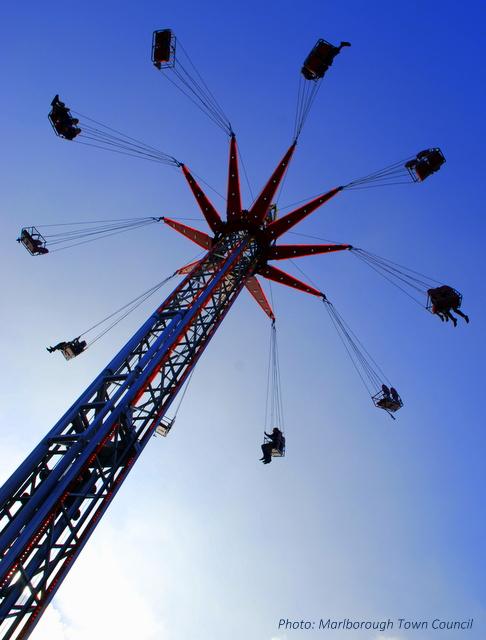A fairground ride swings people around a pole at a great height