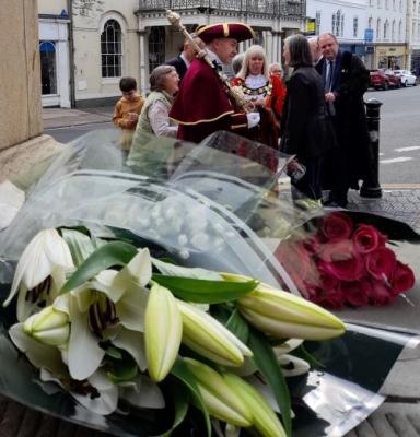 flowers are laid on a stone surface.  There are people in the background