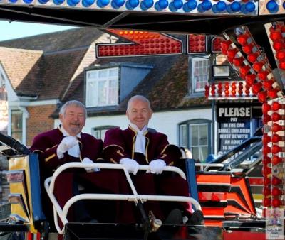 two men wearing ceremonial robes sit in a fairground ride