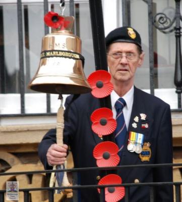 a man in uniform tolls a large brass bell