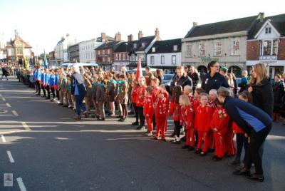 young children in coloured uniforms stand in rows in a street