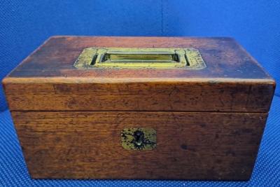 a wooden box with brass handle and key escutcheon